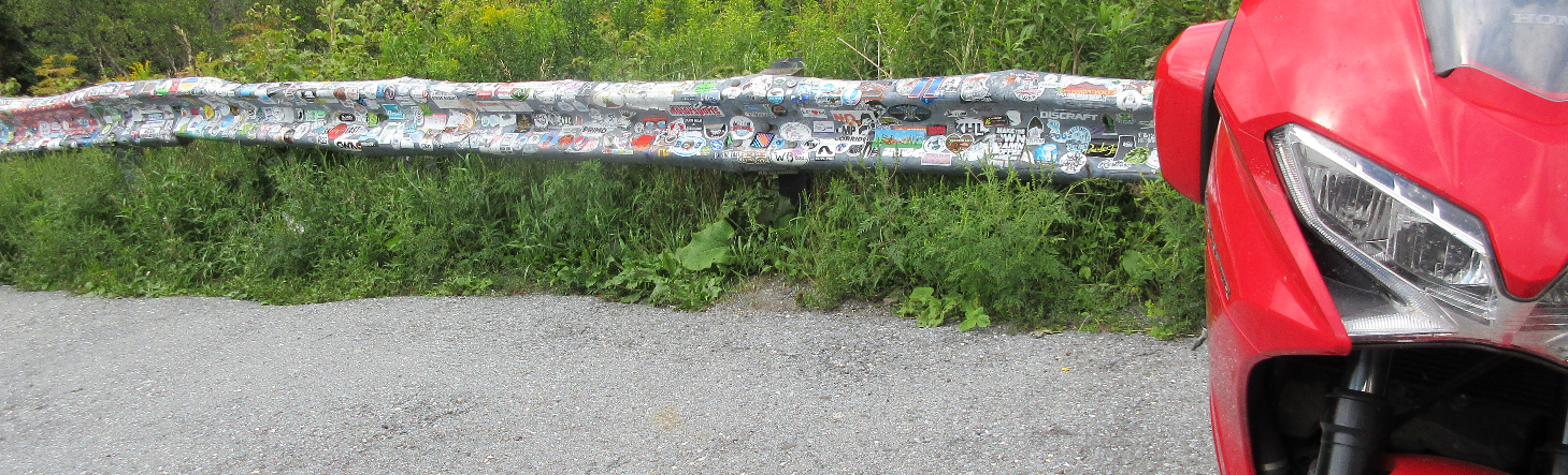 Red Honda VFR parked by a guardrail covered in stickers