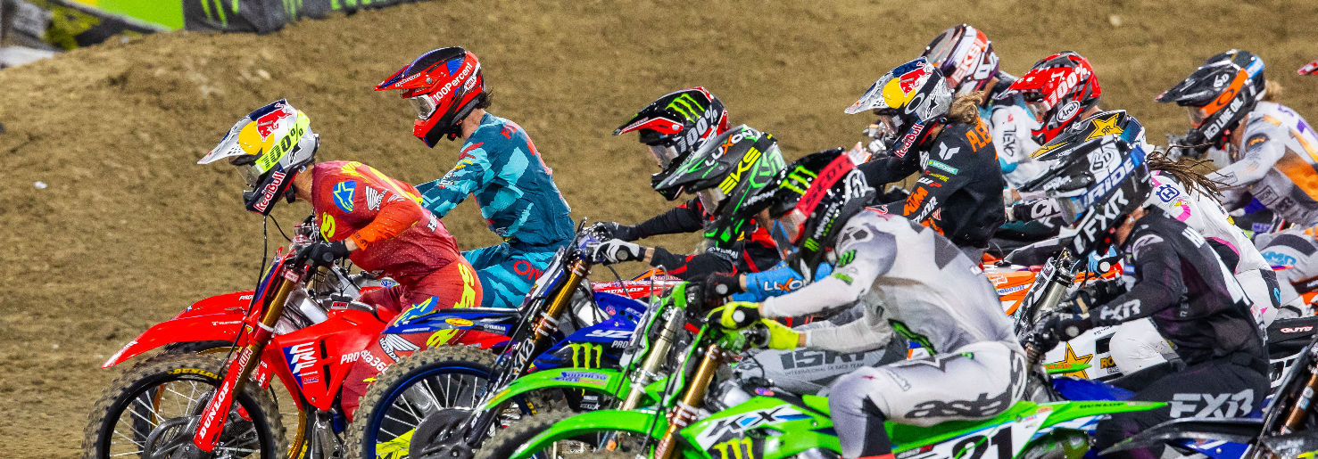 A tight pack of riders leaves the starting gate at the San Diego Supercross race.