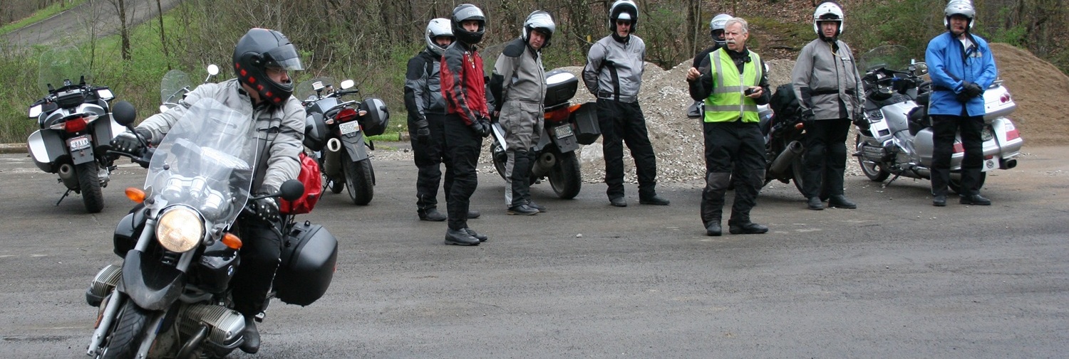 Rider demonstration slow-speed maneuvers on a motorcycle to a class in a parking lot