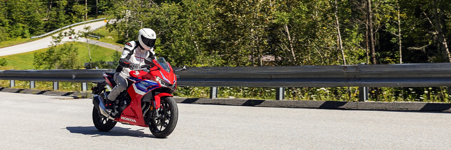 Rider on a red Honda CBR500R on a curving country road